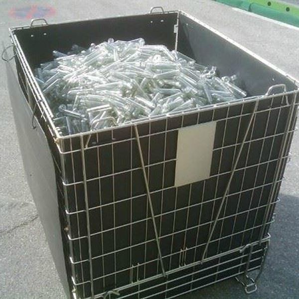 A wire container with PET preforms on the ground.