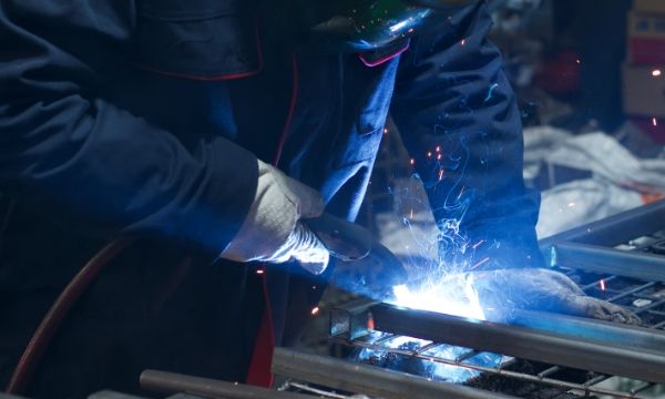 Un trabajador está soldando los marcos de contenedores de alambre.