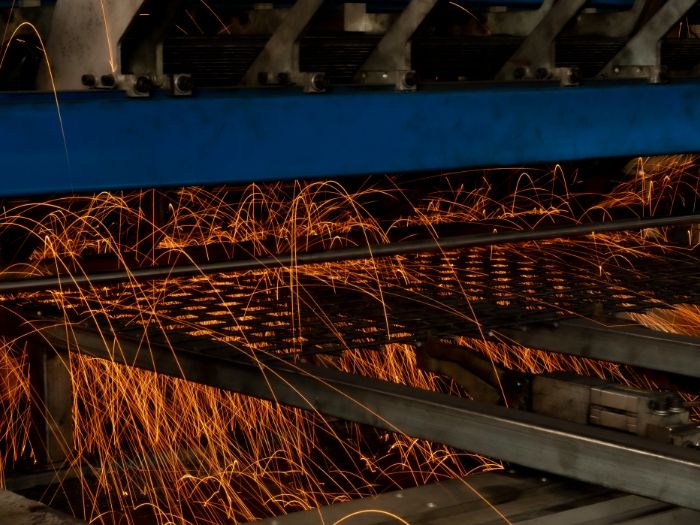 A machine is welding the wire container panels.